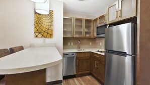 Een moderne keuken met houten kastjes, roestvrijstalen apparatuur en een wit aanrecht.