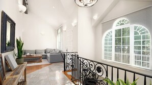 Ein großzügiger Wohnbereich mit grauem Sofa, einer Holzbank und einem Blumentopf.