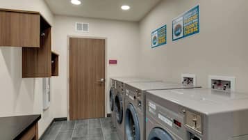 A laundry room with a wooden cabinet, a washing machine, and a dryer. There are signs on the wall and a door labeled "Mechanical."
