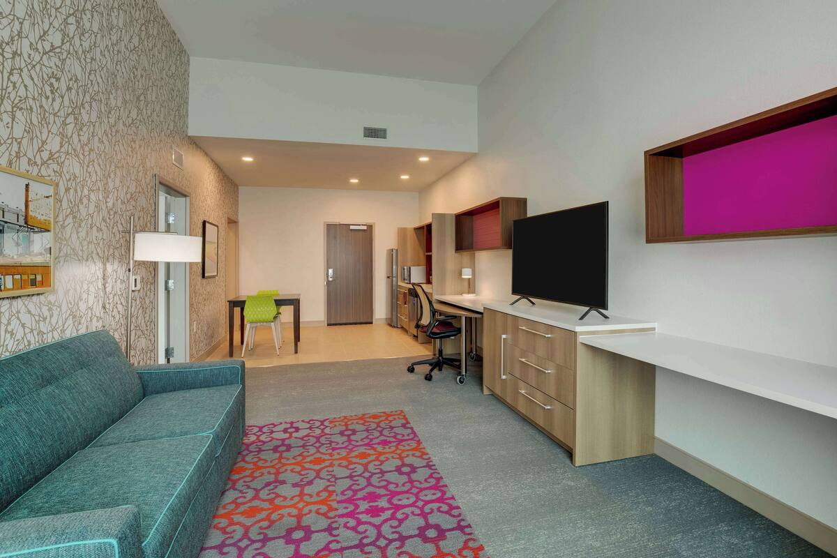 Uma sala de estar moderna com sofá, TV e área de escritório.