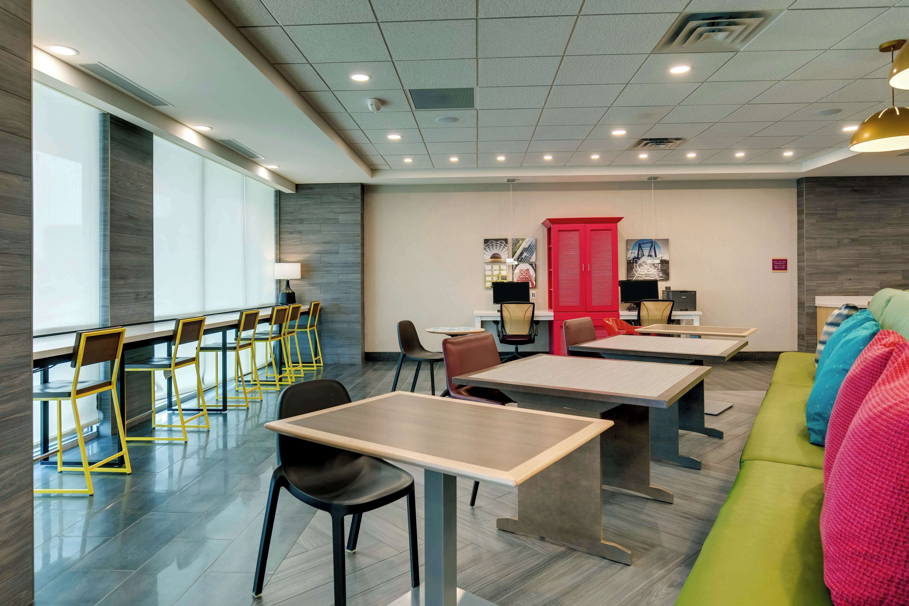 A modern conference room with tables and chairs, a sofa, and a red door.