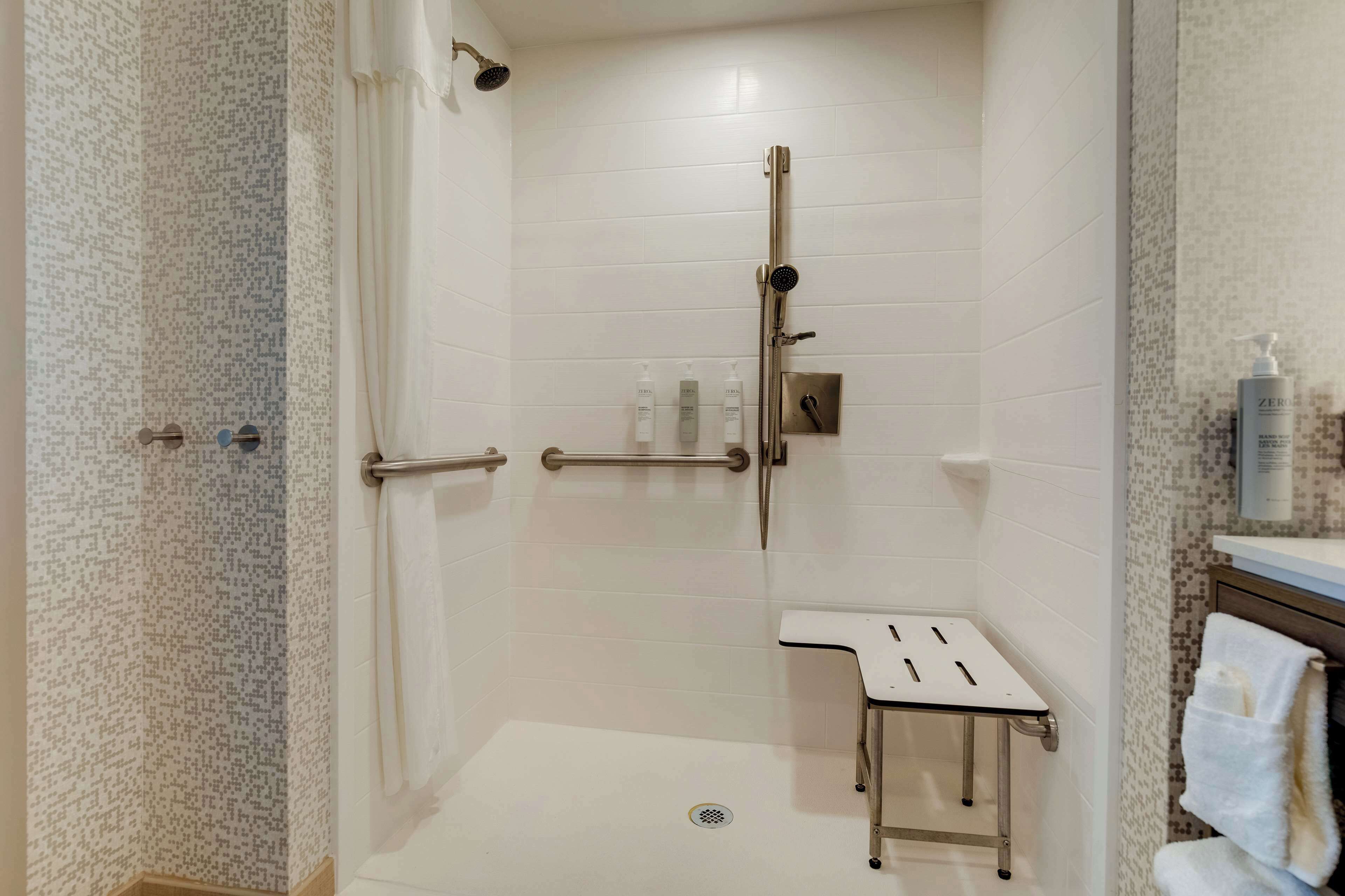 Casa de banho moderna com chuveiro, sanita e lavatório.