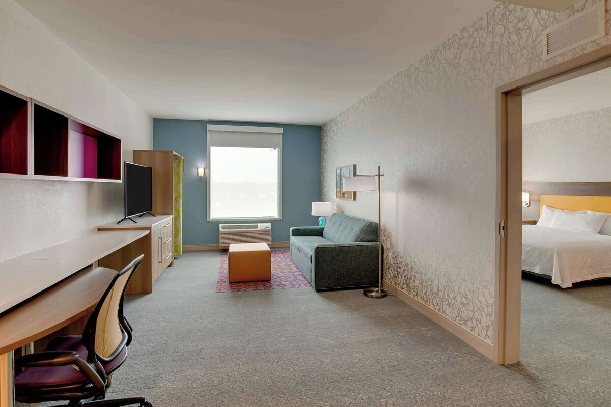 Quarto de hotel com escrivaninha, cadeira, sofá e cama.