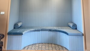 Une pièce avec un banc rembourré bleu, une tête de cerf fixée au mur et un plafond en pente.