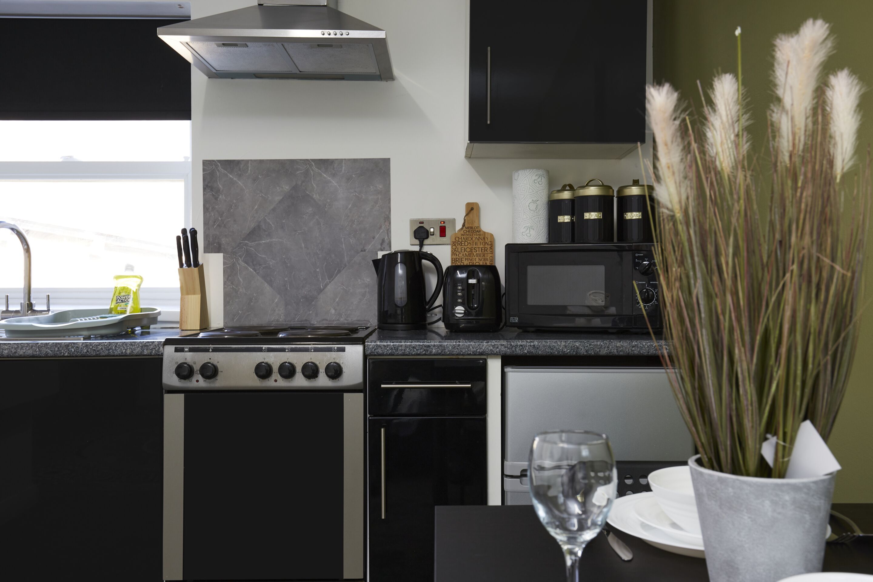 A modern kitchen with a stove, microwave, and coffee maker.