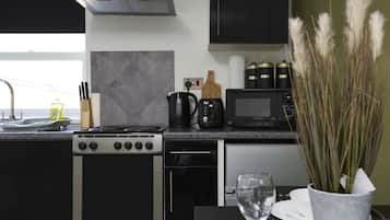 A modern kitchen with a stove, microwave, and coffee maker.