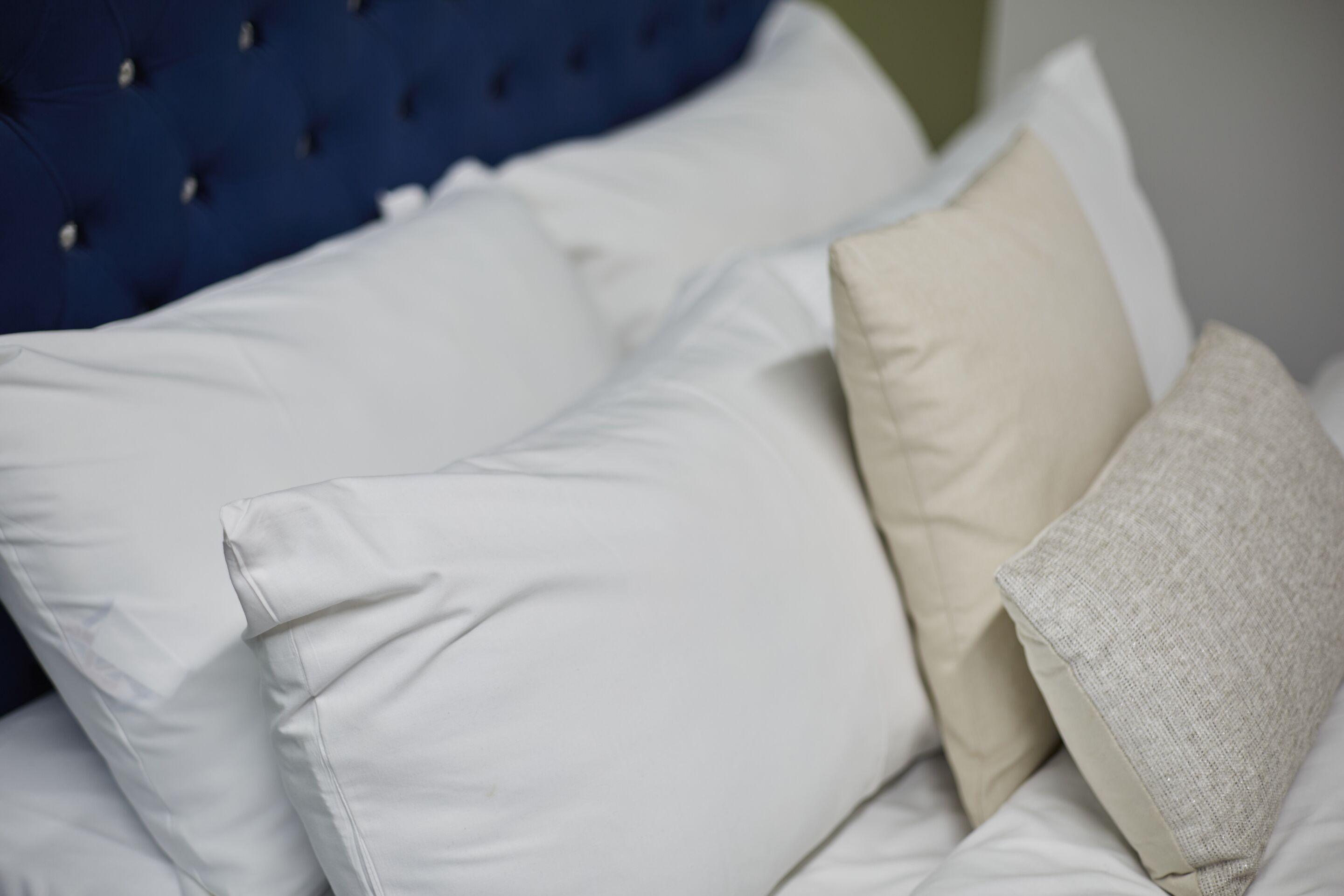 A bed with multiple pillows and a blue headboard.