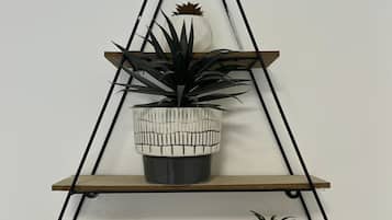 A triangular wall-mounted shelf with three levels, each holding a plant.