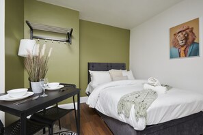 A bedroom with a bed, bedside table, lamp, and a painting of a lion. - Hayy Vibrant Studios Queensgate (Huddersfield)