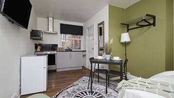 A compact room with a kitchenette, a dining area, and a bed.