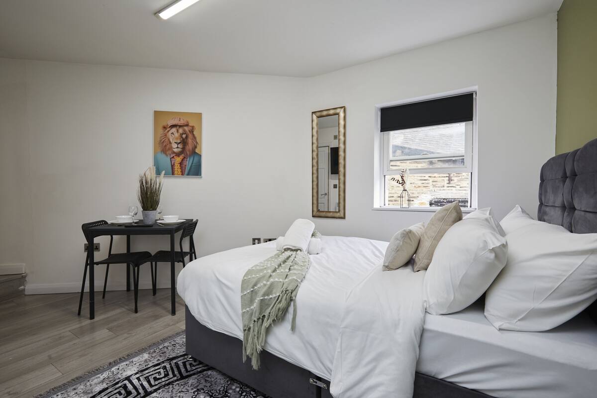 Une chambre à coucher avec un lit, un bureau, une chaise, un miroir et une fenêtre.