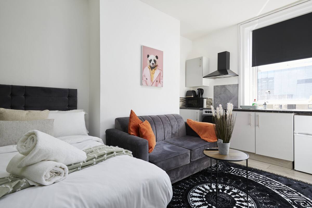 Une chambre d’hôtel moderne avec un lit, un canapé gris et une petite table à manger.
