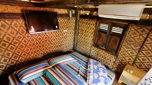 Een kamer met een bed, behang, een wandgemonteerde televisie en een airconditioning.