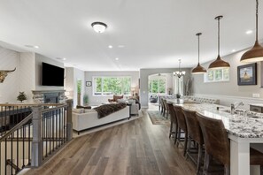 A spacious kitchen with a large island, wooden flooring, and pendant lighting. - Cozy Waconia Escape Near Lakes, Wineries & Downtown (Waconia)