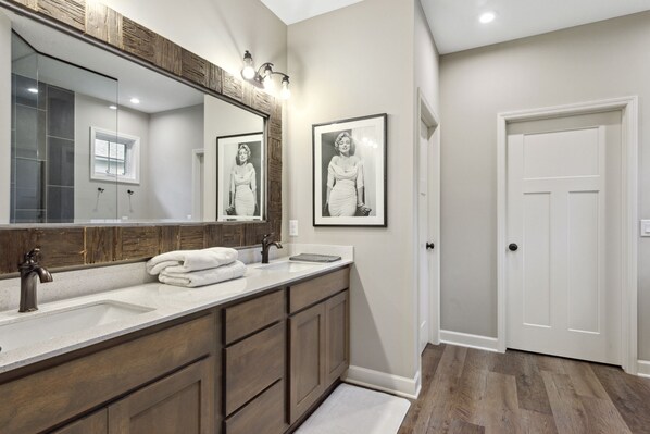A bathroom with a double sink, wooden cabinets, a large mirror, and framed pictures on the wall. - Cozy Waconia Escape Near Lakes, Wineries & Downtown (Waconia)
