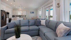 Ein modernes Wohnzimmer mit einem grauen Ecksofa, einem weißen Couchtisch und einer Topfpflanze.
