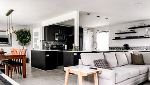 Una sala de estar moderna con un piano, un sofá y un comedor.