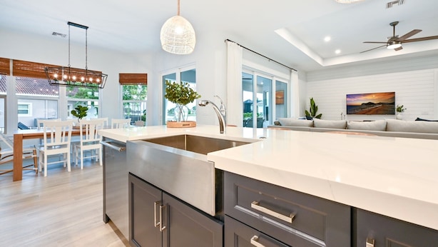 A modern kitchen with a large island, stainless steel appliances, and a dining area with white chairs. - Hot Tub & Heated Pool, 8 Bikes, 2 King Beds and Suites! (Marco Island)