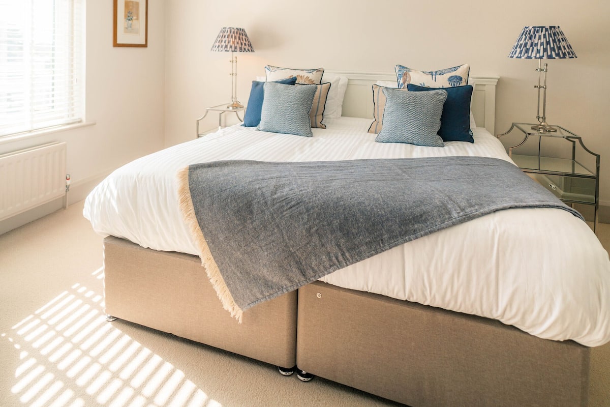 A bedroom with a bed, two bedside tables, a window, and a ceiling light.