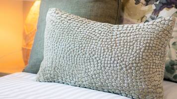 A bed with striped bedding, a green pillow, and a patterned pillow.