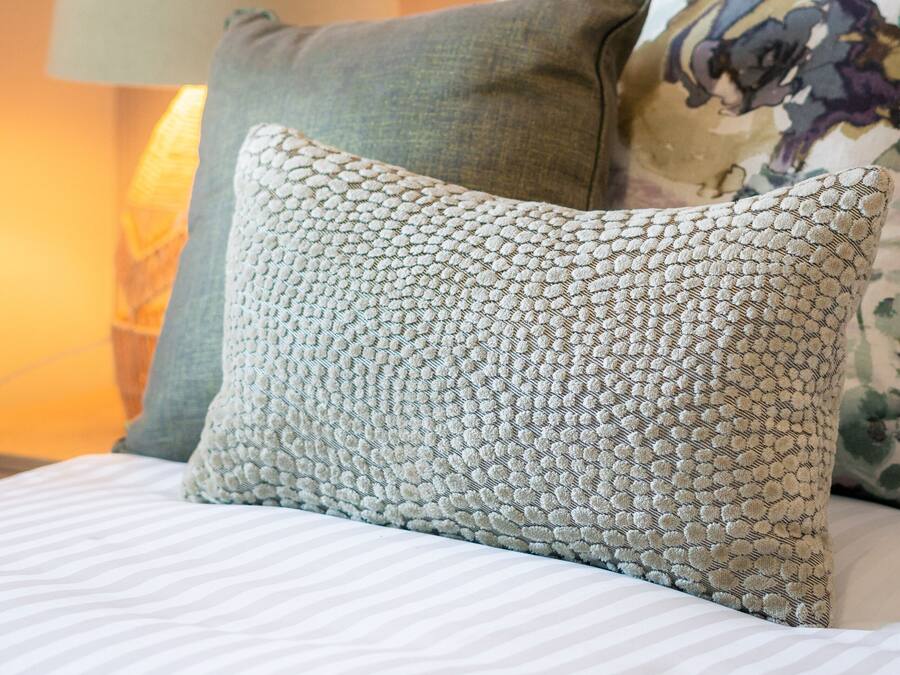 A bed with striped bedding, a green pillow, and a patterned pillow.