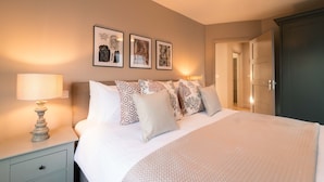 A neatly made bed with patterned pillows, a bedside lamp, and framed artwork on the wall.