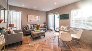 A modern living room with a sofa, ottoman, and dining area with chairs and a table.