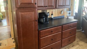 Una cocina con armarios de madera, una cafetera y una botella de vino.