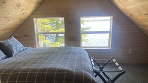 Un dormitorio con cama, dos ventanas y vistas a un lago.