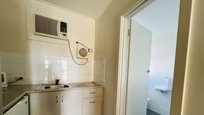 Cozinha compacta com pia, armários e ar-condicionado fixado na parede.