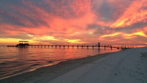 Un muelle se adentra en aguas tranquilas durante la puesta de sol, bajo un cielo despejado.