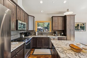Enjoy a kitchen with dark cabinetry, stainless steel appliances, and a large window offering a view of the surrounding landscape.