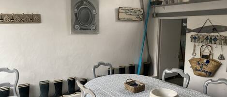 Uma área de refeições com uma mesa redonda, cadeiras, uma cesta e uma tigela.