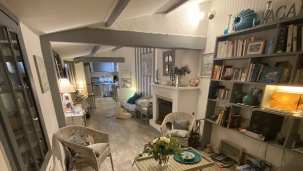 A cozy living room with a sofa, chairs, a coffee table with flowers, a fireplace, and a bookshelf.