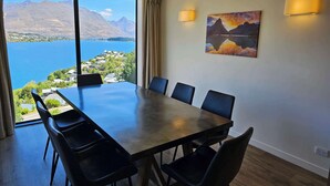Ein Konferenzraum mit einem großen Tisch und sechs Stühlen, einem Gemälde an der Wand und Blick auf Berge und einen See.