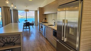 Eine moderne Küche mit Edelstahlkühlschrank, Holzschränken und einem Essbereich mit Bergblick.