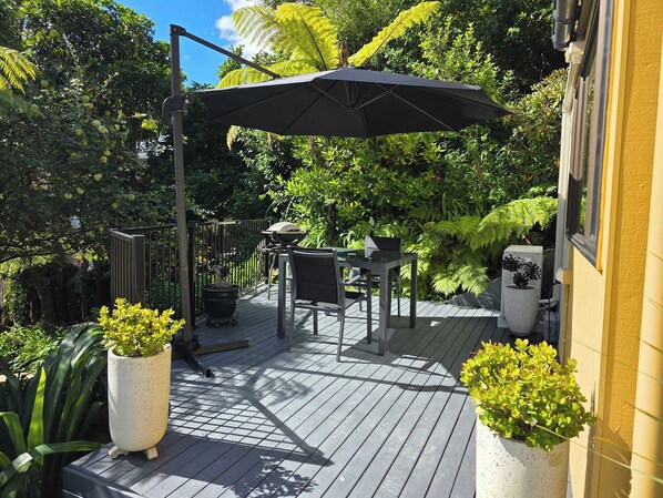 A deck with a table and chairs, a grill, and potted plants. - Beautiful Apartment Surrounded by Native Bush (Picton)