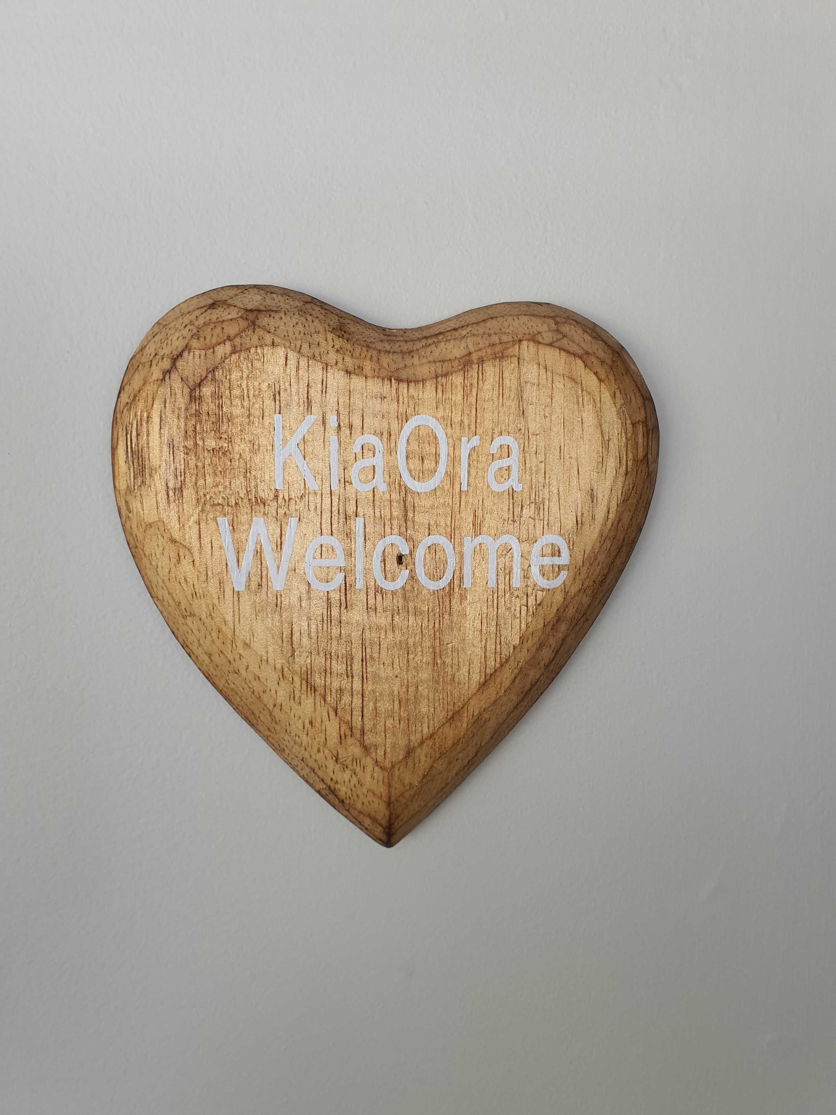 A heart-shaped wooden sign with the text "KiaOra Welcome".