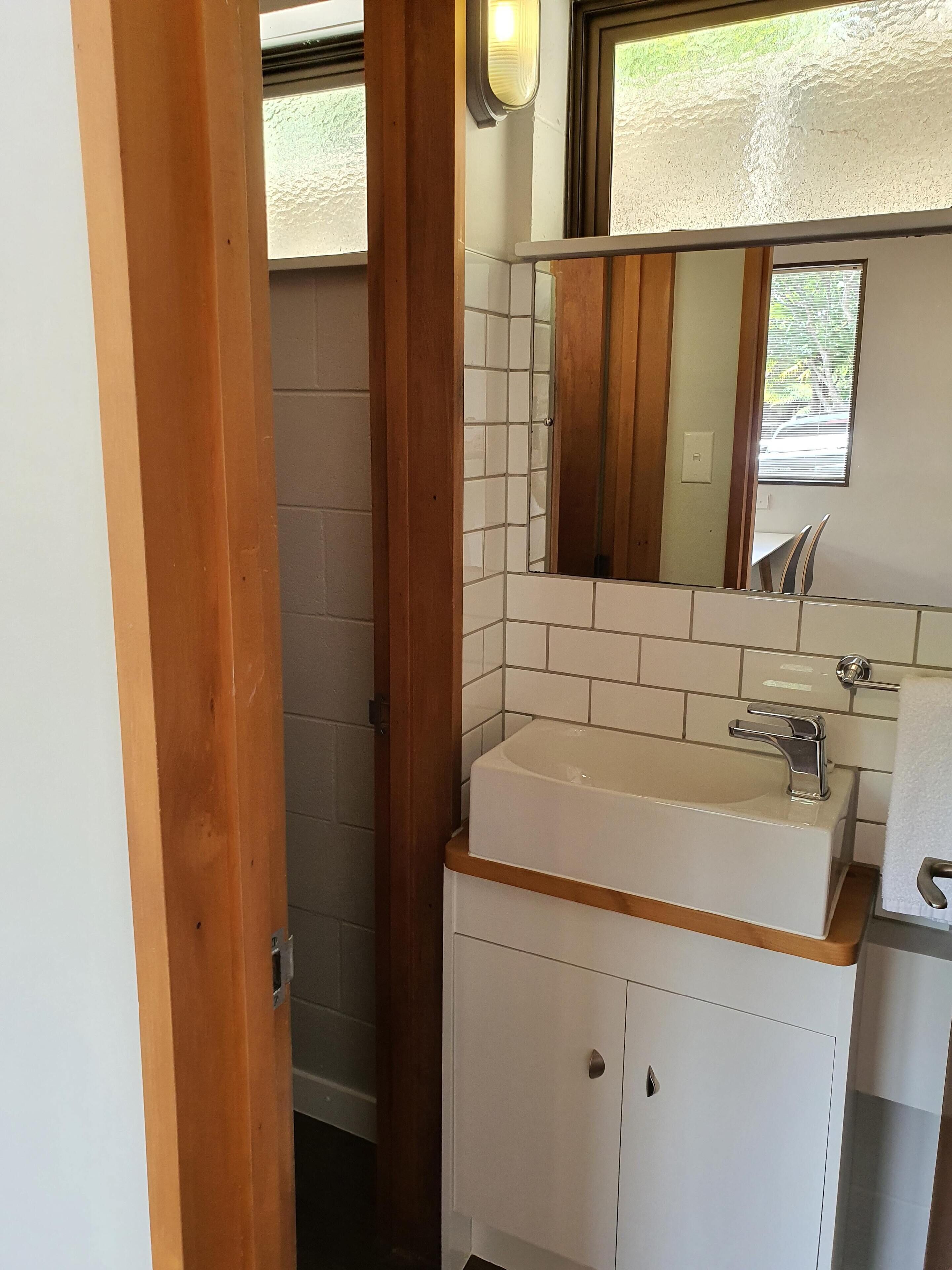 A bathroom with a white sink, a mirror, and a wooden door.