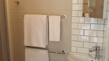 Ein Badezimmer mit Dusche, Waschbecken und Spiegel.