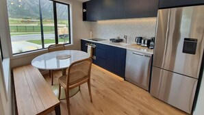 Eine moderne Küche mit Essbereich, großen Fenstern und Blick nach draußen.