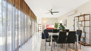 Un espace repas moderne avec une table, des chaises et un téléviseur en arrière-plan.