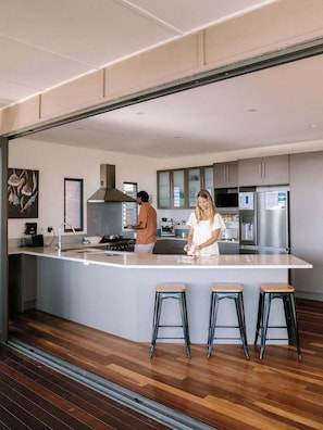 A modern kitchen with a central island, stainless steel appliances, and wooden flooring.
