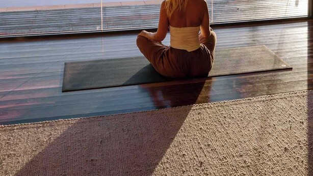 A person meditating on a yoga mat in a room with large windows overlooking a scenic landscape. - Wilderness House l Infinity Pool & Views (Kulangoor)