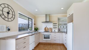 A modern kitchen with white cabinetry, a built-in oven, a gas stove, and a large window.