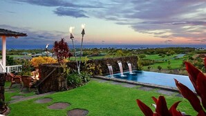 A pool with a waterfall, a gazebo, and a view of a golf course at sunset. - Gorgeous Poipu Villa with Pool & Spa + Ocean Views (Koloa)