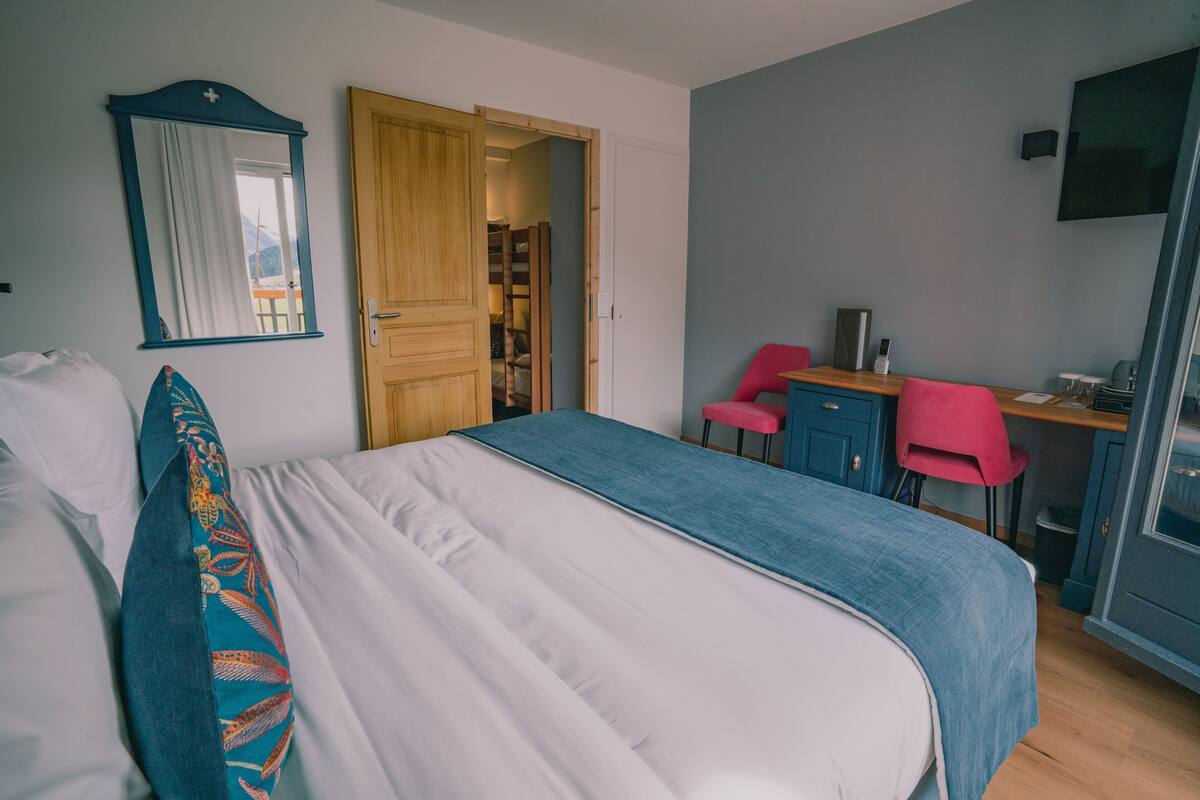 Ein Schlafzimmer mit Bett, Schreibtisch mit Stuhl, Kleiderschrank und Fernseher an der Wand.