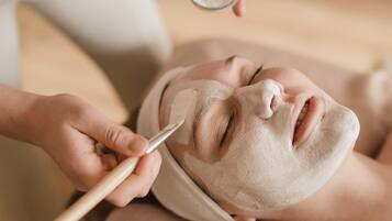 A person receiving a facial treatment with a wooden tool.