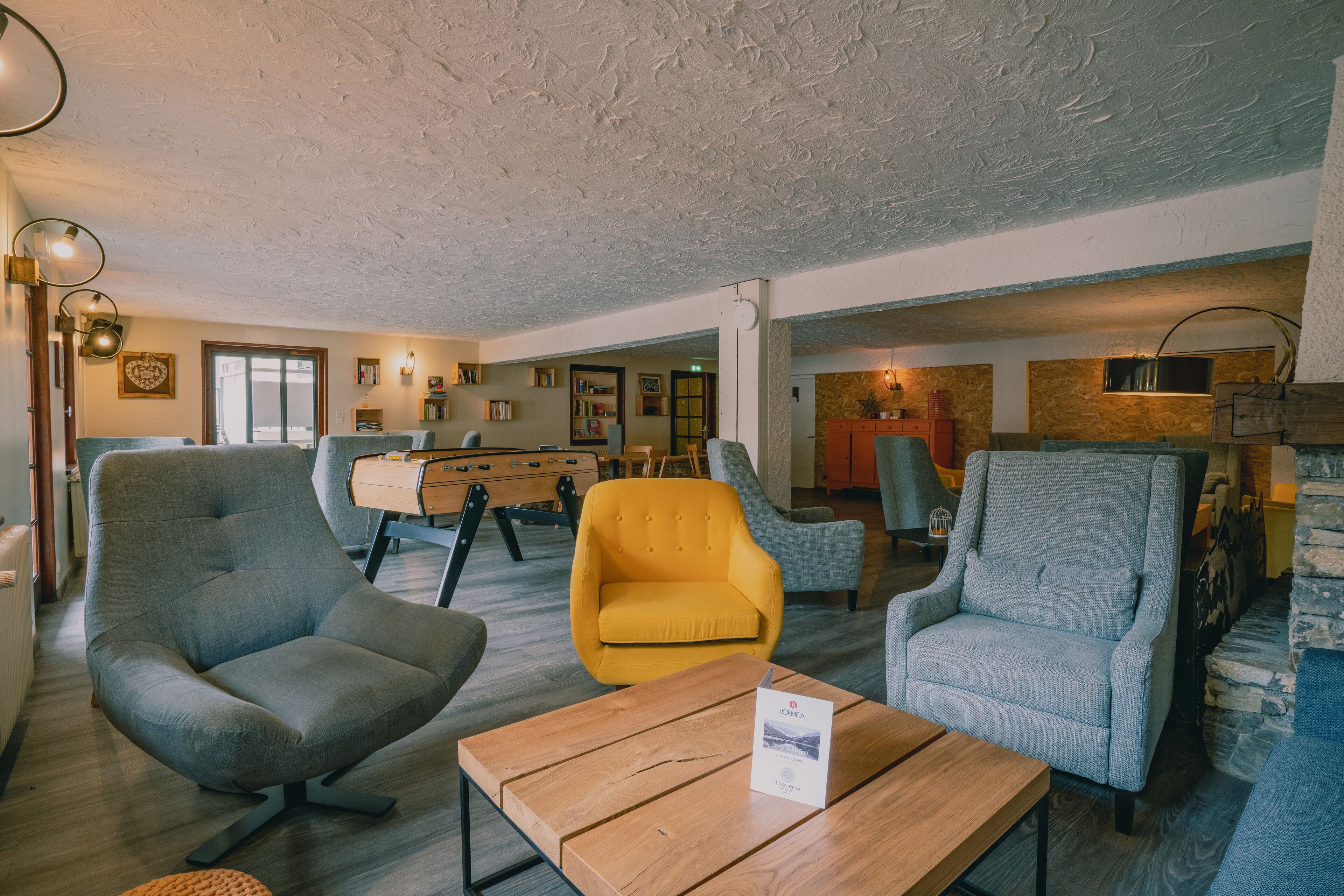 A spacious living area with modern furniture, including a wooden coffee table and multiple armchairs.