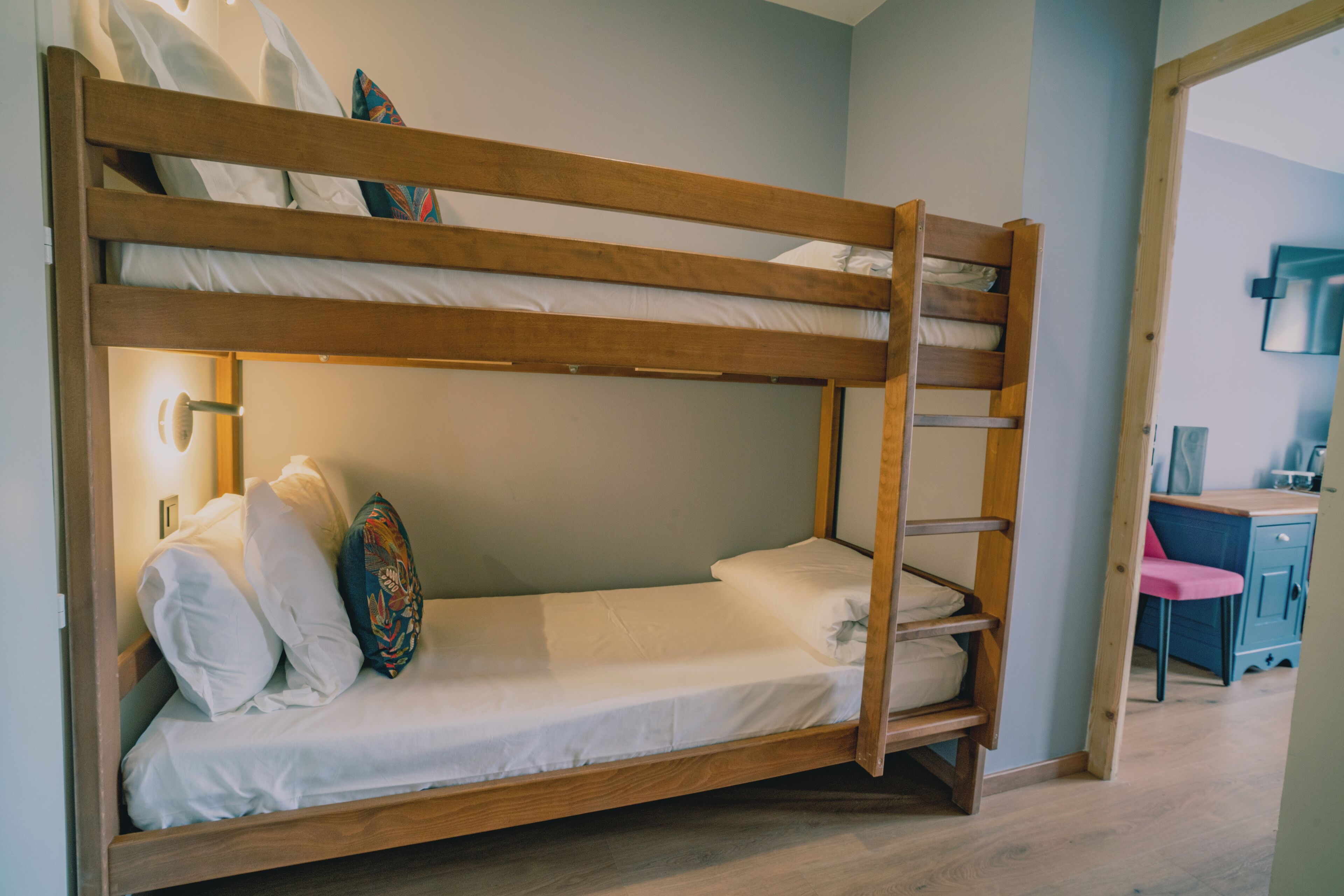 A bunk bed with a ladder, white bedding, and decorative pillows.